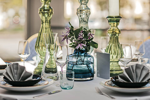 Tischdeko mit grünen Vasen und Blumen